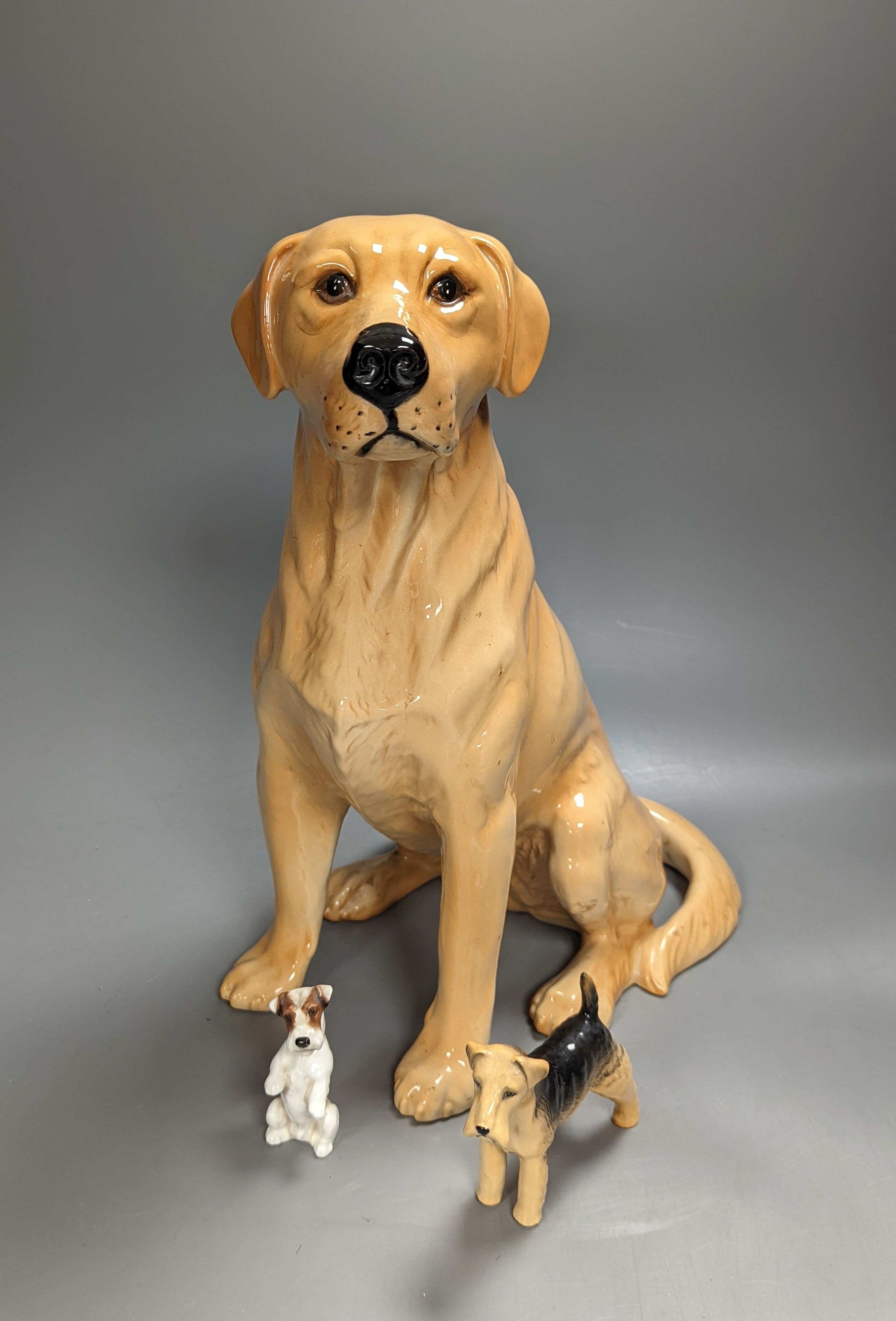 A Royal Doulton figure of a seated Labrador (No. 2314), height 34cm, a small Beswick Airedale Terrier and another (3)